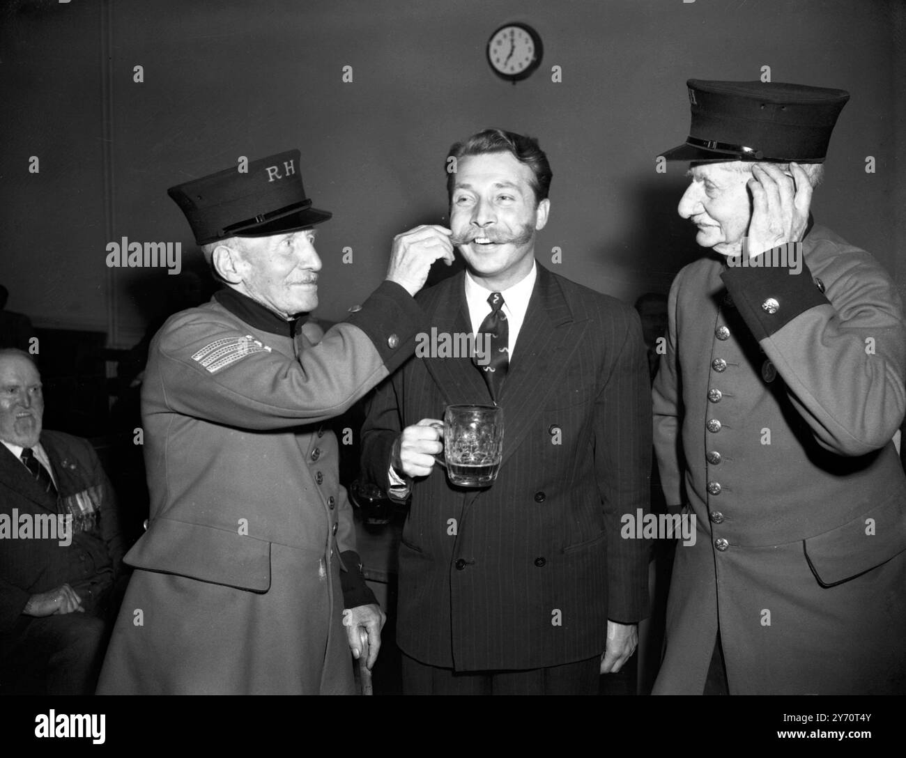 Des membres du club de guidons , dont Raymond Glendening , leur président , ont visité le Victory Club (ex-services) , à Seymour Street , Marble Arch , Londres , pour un match de fléchettes contre l'équipe du club . Une fléchette de quatre pieds a été mise à disposition pour le match. - - Photos : de gauche à droite, STG Simmons , fin de la Brigade des fusils , 77 ans, pensionné de Chelsea , M. Edward Hooker , de Hearne Hill , avec sa moustache de guidon de 9 1/3 pouces et le Pte J H Davey âgé de 83 ans , pensionné de Chelsea , admirer E hookers guidon. - - 18 juillet 1949 Banque D'Images