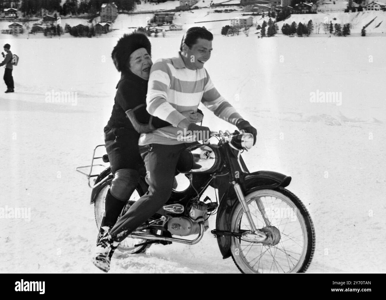 Il a l'hôtesse avec le mostest sur le dos. St Moritz, Suisse : L'homme qui a comme passager à l'arrière de sa moto la 'hôtesse avec le plus mostest', Elsa Maxwell, chevauchant le lac est Gunter Sachs von Opel, célèbre sportif millionnaire allemand. Il appartient à la famille des constructeurs automobiles Opel. La veille du nouvel an, il s'est secrètement fiancé à Mara Lane, l'actrice. 20 février 1959 Banque D'Images