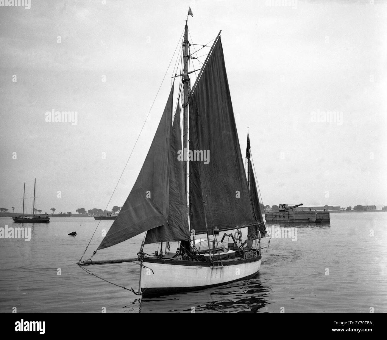 Edward Allcard , Surrey , Angleterre , a navigué de Gibraltar aux Etats-Unis dans un ketch de 29 pieds , seul , en 81 jours . Au cours de son voyage, il a été assailli par des requins, endeuillé, et laissé des cloques dans le soleil chaud au large des Bermudes , jeté à peu près comme un bouchon dans les vents et les tempêtes de l'Atlantique . Il l'a fait parce qu'il n'aimait pas l'austérité de l'Angleterre. Photos : Edward Allcard à la barre de son ketch , Temptress , à son arrivée à New York après la traversée de l'Atlantique le 15 août 1949 Banque D'Images