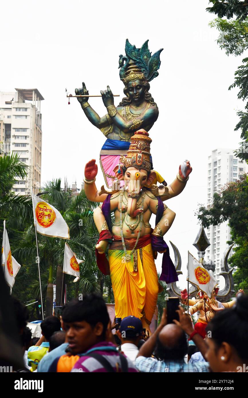 Festival Ganesha Chaturthi à Mumbai, Inde les dévots apportent une idole du Seigneur Ganesha avec l'idole du Seigneur Krishna en toile de fond, le Dieu hindou à tête d'éléphant de la sagesse, de la prospérité et de la bonne fortune, avant le festival Ganesh Chaturthi, à Mumbai, Inde, le 25 août 2024. Ganesh Chaturthi est un festival hindou populaire qui célèbre la naissance du Seigneur Ganesha et il dure généralement dix jours, commençant le quatrième jour Chaturthi du mois hindou de Bhadrapada, qui tombe généralement entre août et septembre dans le calendrier grégorien. L'installation d'idole dans les maisons et sous les tentes make-shift est follo Banque D'Images