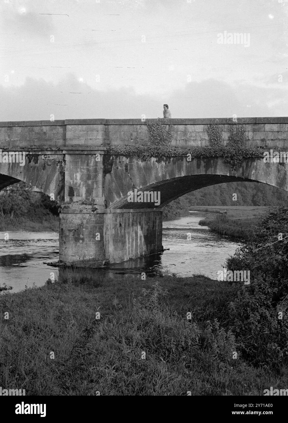 Femme de pont de pierre regardant au-dessus du parapet à la rivière 1946 Banque D'Images