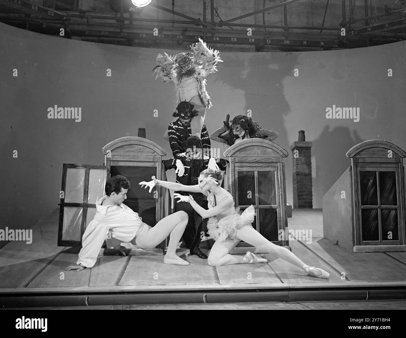 LA TÉLÉVISION BRITANNIQUE VA TOUT FRANÇAIS la dernière contribution de la télévision à l' ''entente cordial'' a apporté une touche de gaieté parisienne au programme britannique lorsque les Ballets de Paris de Roland petite ont donné une représentation au Alexander Palace Studio de Londres , ils sont l'une des nombreuses compagnies de ballet françaises amenées en Angleterre pour une série de programmes . L'IMAGE MONTRE:- '' Ballet of Cats '' Roland petit ( à gauche) le seul '' être humain '' dans ce ballet insolite -avec le chat blanc (Colette Marchland ) et la compagnie de ballet complète en arrière-plan , pendant le programme . 3 Banque D'Images
