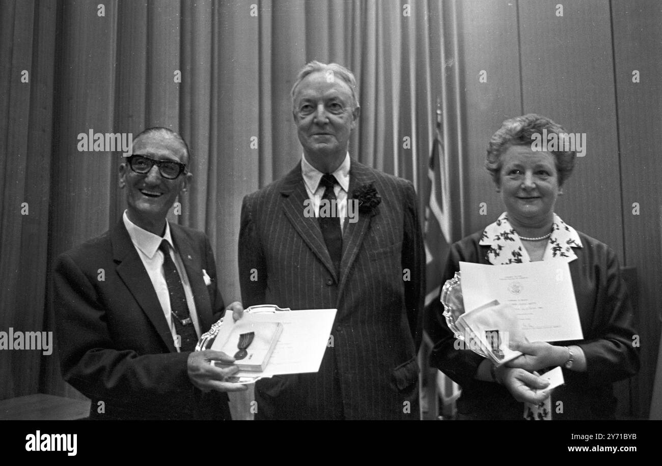 L'ambassadeur américain, M. David Bruce (au centre), a honoré deux de ses collaborateurs, M. Herbert Couzens , spécialiste du budget et de la fiscalité , lors d'une cérémonie marquant sa retraite après 48 ans à l'ambassade des États-Unis et Mlle Mildred O Smith avec 41 ans de service . M. Couzens est arrivé à la dure , commençant sa carrière comme messager à 14 ans . Il a servi 17 ambassadeurs et, à ses débuts, il se souvient d'avoir dû porter un costume bleu à col blanc rigide ' pour garder la tête haute ' , et d'avoir été équipé de 12 paires de gants blancs . Son moment le plus fier a été reconnu par feu le président John F K Banque D'Images