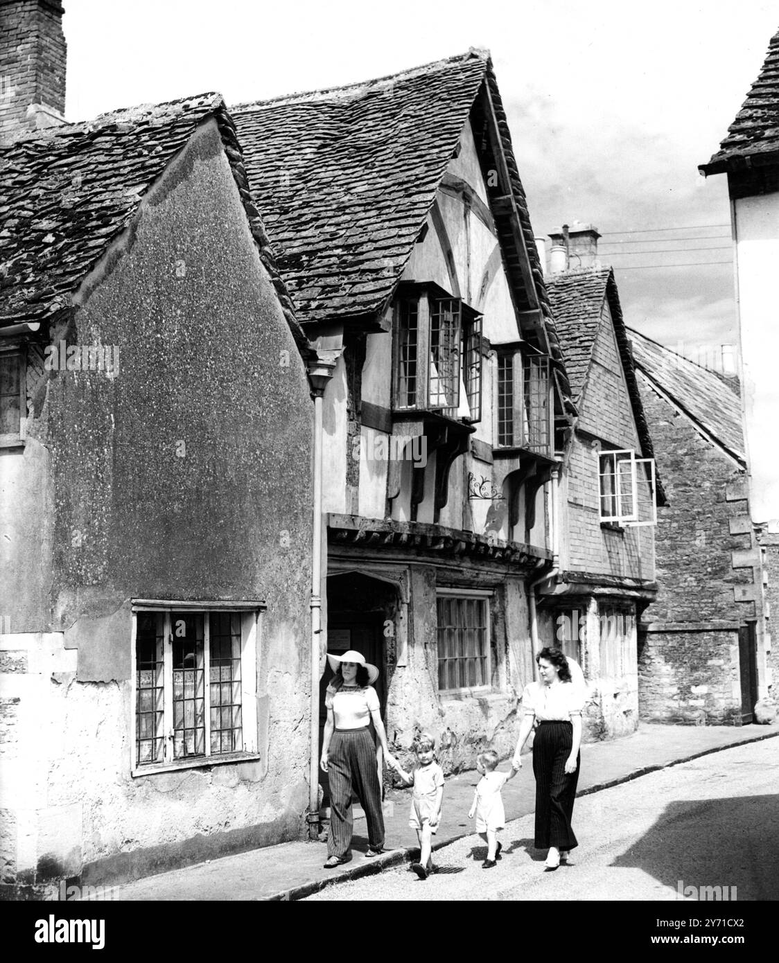 Marcher dans le passé dans l'atmosphère sereine et délicieuse du vieux village du monde de Lacock dans le Wiltshire, avec ses petites rues pittoresques et ses cottages aux poutres en chêne est une source d'intérêt sans fin pour les vacanciers. Cette image montre andAngel Inn qui est un joyau du 16ème siècle de l'antiquité et l'un des nombreux beaux monuments de ce village ancré dans le passé. 16 août 1949 Banque D'Images