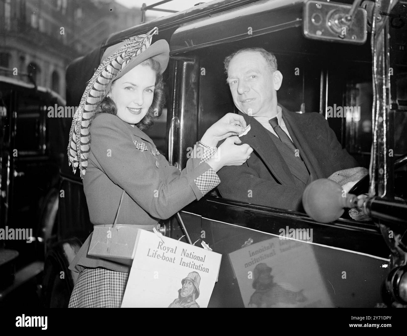 LA JOURNÉE DU BATEAU DE SAUVETAGE À LONDRES "AIDÉE PAR LES ÉTOILES" en relation avec l'appel de rue annuel pour le service des bateaux de sauvetage, par la Royal National Life-Boat institution, aujourd'hui, la star de l'écran PATRACIA ROC et la danseuse BARANOVA ont aidé à collecter des boîtes à l'hôtel Claridge. L'IMAGE MONTRE:- PATRICIA ROC portant un chapeau de printemps frappant à plumes de faisan, vend un emblème de bateau de sauvetage à un chauffeur de taxi à Londres ce matin. 11 mai 1948 Banque D'Images