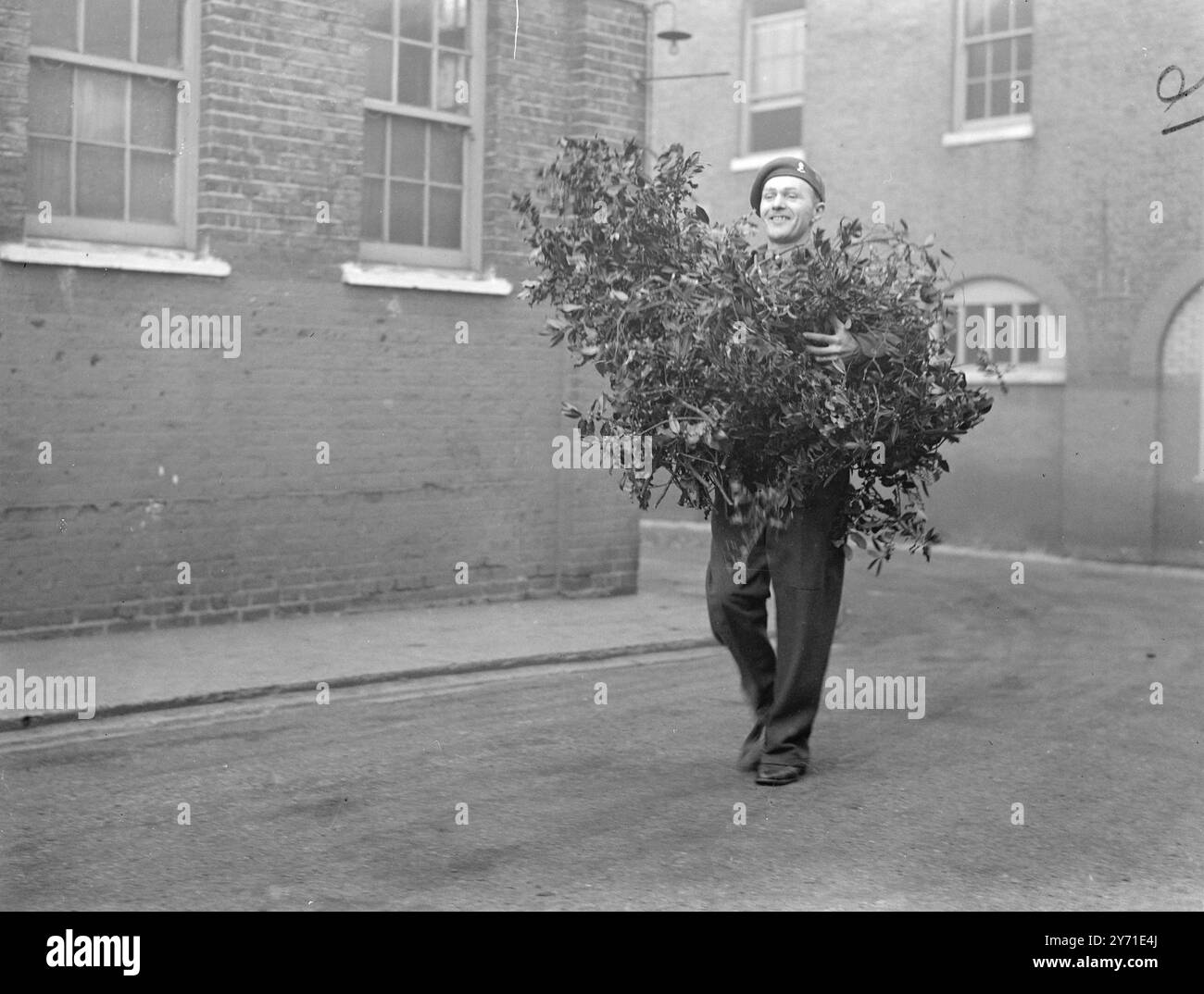 ARMIES FESTIVE MOOD - L'esprit de Noël de l'armée est capturé dans cette photo heureuse de Bombadier, ARTHUR J. GIBB, de Surbiton, Surrey, qui tient une armure de Holly et Mistletoe destinée à faire le dépôt Royal Artillery à Woolwich, un peu plus lumineux pour les festivités de Noël. - 17 décembre 1948 Banque D'Images