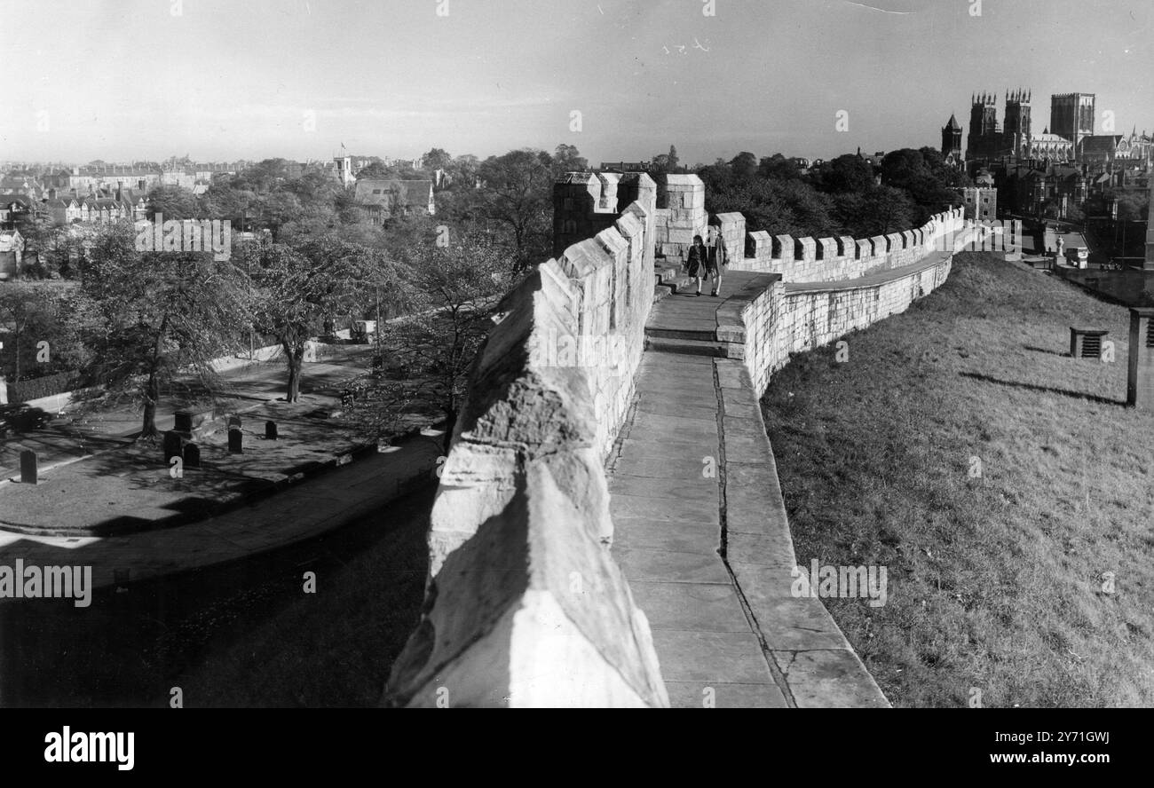 Rappel des temps anciens. Pittoresque et typique de la scène anglaise est la promenade le long de la muraille romaine qui longe cette célèbre ville. York - le ministre peut être vu en arrière-plan - est l'un des rares endroits où les murs médiévaux sont encore intacts, presque dans leur état d'origine. Seules quelques modifications ont été apportées et celles-ci ont été dues à des réparations et à des problèmes de circulation. Les murs actuels ont été construits en pierre apportée de Tadcaster au XIIIe siècle. Un ennemi souhaitant entrer dans York au moyen âge a trouvé une barrière redoutable devant lui. 1952 Banque D'Images