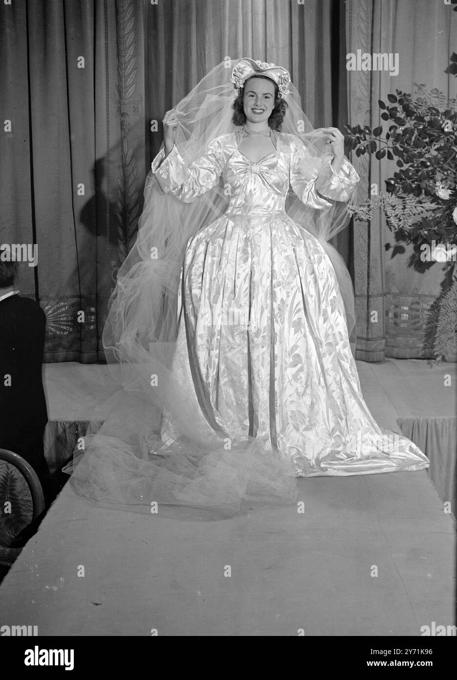 Robe Panniered en broche blanche et argentée'. La robe de tête de fleur de Marie et un petit train complètent un ensemble charmant. C'est l'un des modèles frappants à être exposé à la Mayfair Parade pendant quatre jours de toutes les parties du monde à l'Hôtel Mayfair , Londres . 22 novembre 1948 Banque D'Images