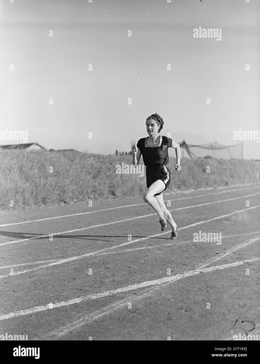 ' DACTYLOGRAPHE À GRANDE VITESSE ' POUR L'ÉQUIPE OLYMPIQUE BRITANNIQUE . Mme DOROTHY MANLEY, âgée de 21 ans, aux cheveux bruns, de Woodford Green, Essex, est un nouvel espoir britannique pour les épreuves féminines des Jeux olympiques de cette année. Découvert par l'ancien athlète international Sandy Dunc d'Oxford , DOROTHY vient de pointer 11. 1 seconde pour les cent yards , une performance qui la classe parmi les meilleures athlètes féminines du monde . L'IMAGE MONTRE :- ' Record Margin ' ' arrêté' par la caméra de vitesse DOROTHY MANELY entre dans une foulée olympique , alors qu'elle sprints en pratique à Woodford Bridge , Essex . Banque D'Images