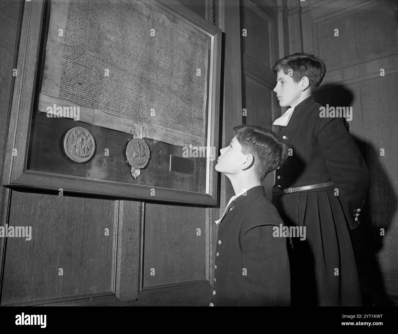 Christ's Hospital School , Horsham, Sussex dans la salle d'audience lambrissée de chêne de l'école John Cooper (à gauche) et Stephen Bedford (13 ans), ont lu un fac-similé photographique de la charte originale donnée à l'école par Edward VI le 12 juin 1553 Banque D'Images