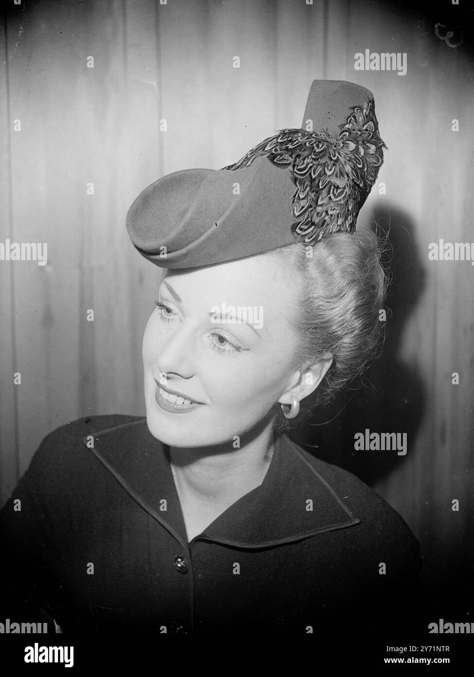 Hauteur de sophistication la Miss bien habillée d'aujourd'hui porte ce chapeau de tricorne en feutre de fourrure de cactus est qu'elle veut paraître sophistiquée. Ses lignes nettes sont brisées par de douces plumes mouchetées qui rehausse cette belle création. 9 août 1948 Banque D'Images