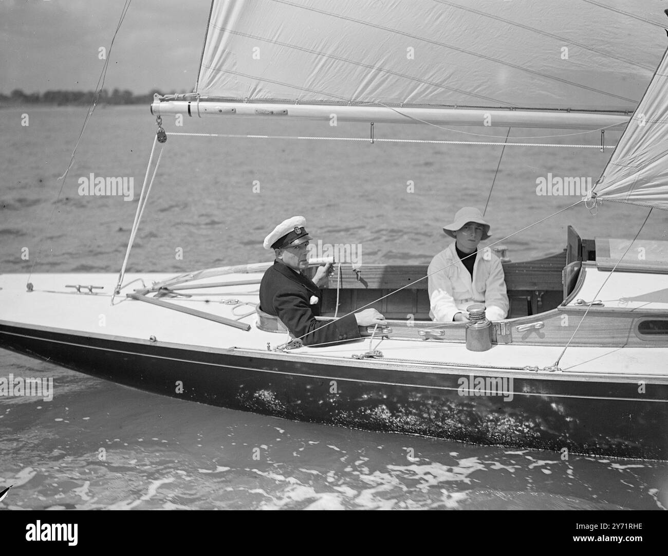 « Royal Yacht on Trials » « Bluebottle », le yacht de course de la classe Dragon, qui sera présenté à leurs Altesses Royales, la princesse Elizabeth et le duc d'Édimbourg, était sorti en voile sur des sentiers s'étendant au large de Hamble, Hants, aujourd'hui. L'image montre : 'au commandement' - Lieutenant commander Crichton, R. N, dirige la 'Bluebottle' pendant ses essais dans le Solent aujourd'hui. 6 juillet 1948 Banque D'Images