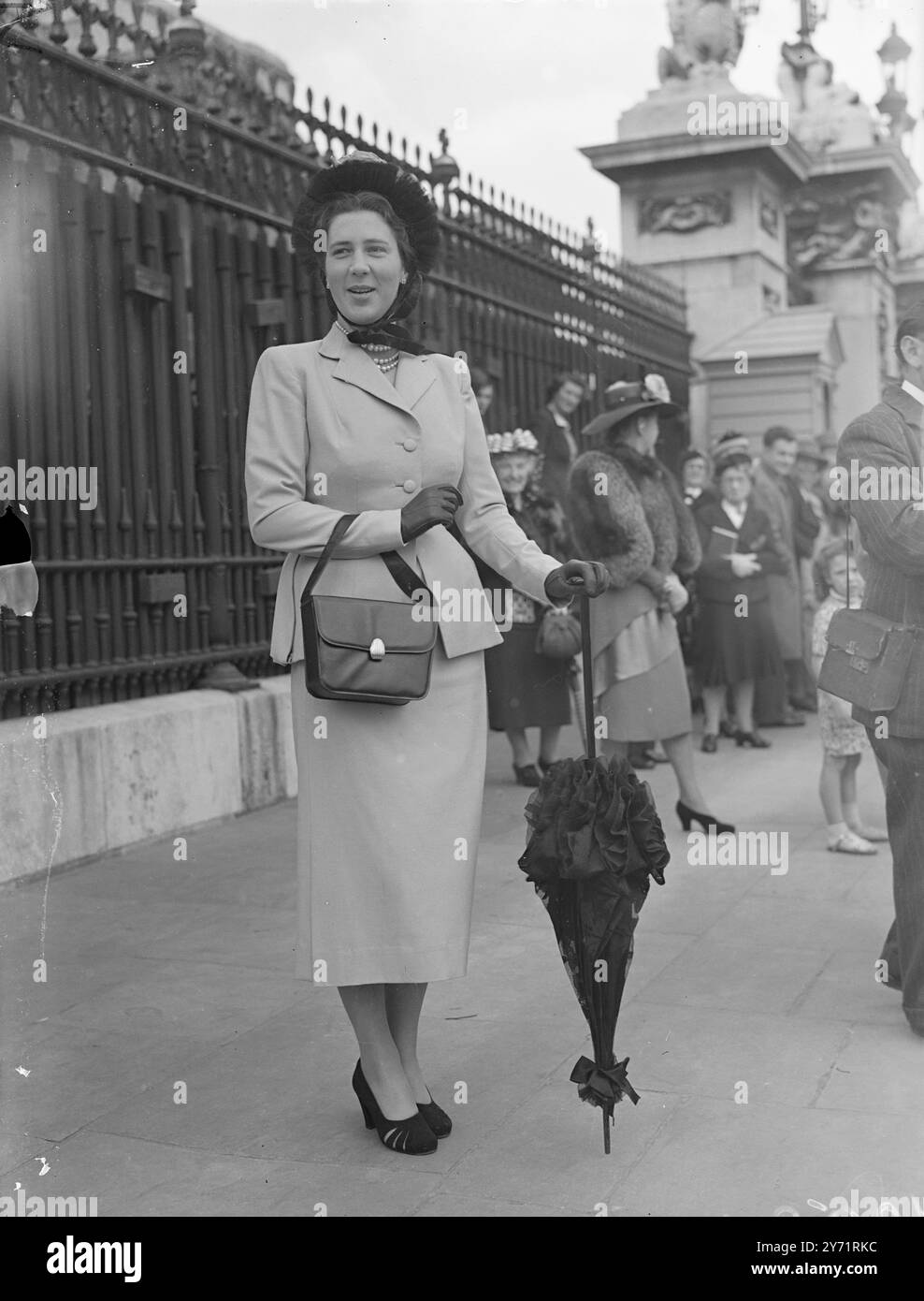 Parasol pour le palais Miss Good - Adams de Chelsea , porte un chapeau noir frappant avec sa robe rose , alors qu'elle assiste à la fête d'après-midi d'aujourd'hui au palais de Buckingham . Un parasol noir et des gants sont des accessoires assortis. 8 juillet 1948 Banque D'Images