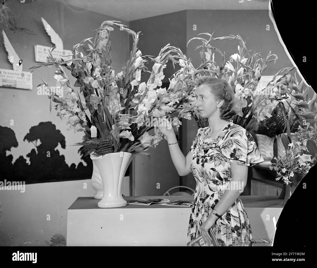 Hall of Beauty Horticultural Show ouvre ses portes. Les amateurs de jardins qui ont assisté à l'ouverture du salon horticole au National Hall, Olympia, ont vu les richesses d'un millier de jardins d'amateurs, côte à côte avec des expositions sophistiquées de pépinières célèbres et de sociétés de jardinage faisant un flambeau glorieux de couleurs et de beauté. Images montrent: "Tout le chemin de Londres" - Miss Beryl Browning, de London, Ontario, Canada, admire un bouquet de Gladioli spécialement transporté à Londres, Angleterre, pour le spectacle horticole. 5 août 1948 Banque D'Images