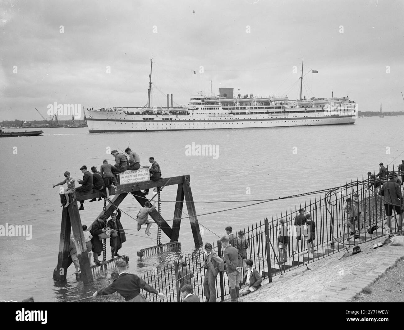 Le navire de troupes 'Dilwara' part pour la Malaisie lorsque son Major Trooper 'Dilwara' part de Southampton pour la Malaisie, il a à son bord 800 officiers et hommes du 4th Hussars et contingent de soeurs infirmières britanniques en route pour Singapour. Images : la 'Dilwara' alors qu'elle commence son long voyage vers l'est. Les garçons pêchant depuis leur stade improvisé au premier plan semblent trop préoccupés pour remarquer le soldat alors qu'elle fait son chemin vers la mer. 20 août 1948 Banque D'Images