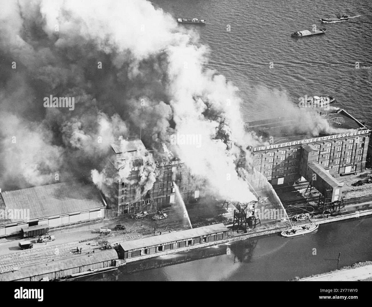 Les vivres brûlent dans l'incendie des docks d'Amsterdam. Un incendie s'est déclaré dans deux des entrepôts frigorifiques les plus grands et les plus modernes d'Amsterdam Docks, tôt le samedi matin. Le feu qui s'est propagé rapidement, s'est nourri des grands magasins de viande, de graisse, de beurre, d'oeufs et de poisson, qui étaient stockés dans les entrepôts pour l'approvisionnement hivernal de la population néerlandaise. L'ensemble des pompiers d'Amsterdam avec tous ses moteurs de conduite et flottants a été appelé sur les lieux de l'incendie. La quantité de nourriture et d'argent perdue dans l'incendie ne peut pas encore être estimée, mais elle s'élèvera certainement à des millions de florins. Photos : Banque D'Images