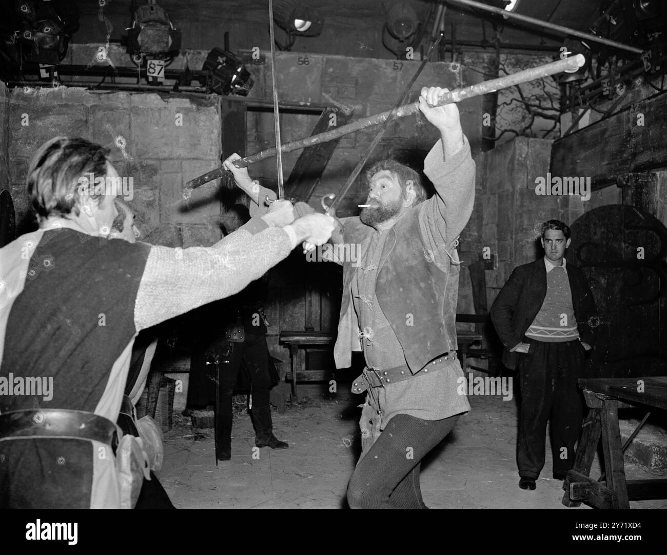 Walton on Thames, Surrey : 'Little John' avec une cigarette anachronique pendante de ses lèvres, répète une scène d'une bataille entre lui et deux hommes du shérif de Nottingham, pour la série télévisée 'Robin des bois'. Little John est joué par Archie Duncan, qui vient de Glasgow, et a joué ce rôle dans plus de quatre-vingt-dix films. 29 octobre 1958 Banque D'Images Walton on Thames, Surrey : 'Little John' avec une cigarette anachronique pendante de ses lèvres, répète une scène d'une bataille entre lui et deux hommes du shérif de Nottingham, pour la série télévisée 'Robin des bois'. Little John est joué par Archie Duncan, qui vient de Glasgow, et a joué ce rôle dans plus de quatre-vingt-dix films. 29 octobre 1958 Banque D'Images