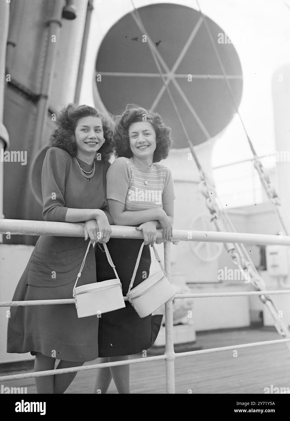 'Quittant Town' lorsque le S.S. Aquitania a quitté Southampton pour le Canada aujourd'hui, transportant des émigrants, les sœurs Elsie (à gauche) âgées de 17 ans et Jean Royce, de Paddington, étaient à bord. Ils portent un sourire assorti, comme leurs sacs à main. 5 juillet 1948 Banque D'Images