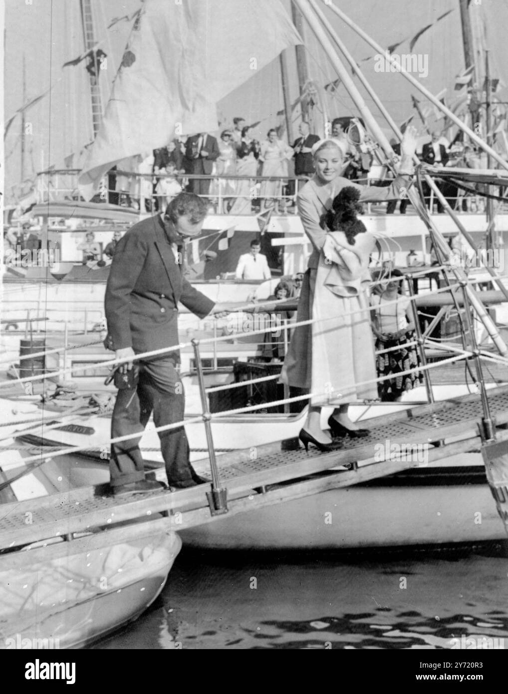 Partez pour leur lune de miel Monaco : le Prince Rainier III et la Princesse Grace Patricia de Monaco, portant son caniche noir, à bord du yacht du Prince, le 'DEO Juvante', à Monaco pour leur lune de miel le long de la côte italienne. Ils sont allés au port depuis le Palais après la réception de mariage. 19 avril 1956 Banque D'Images