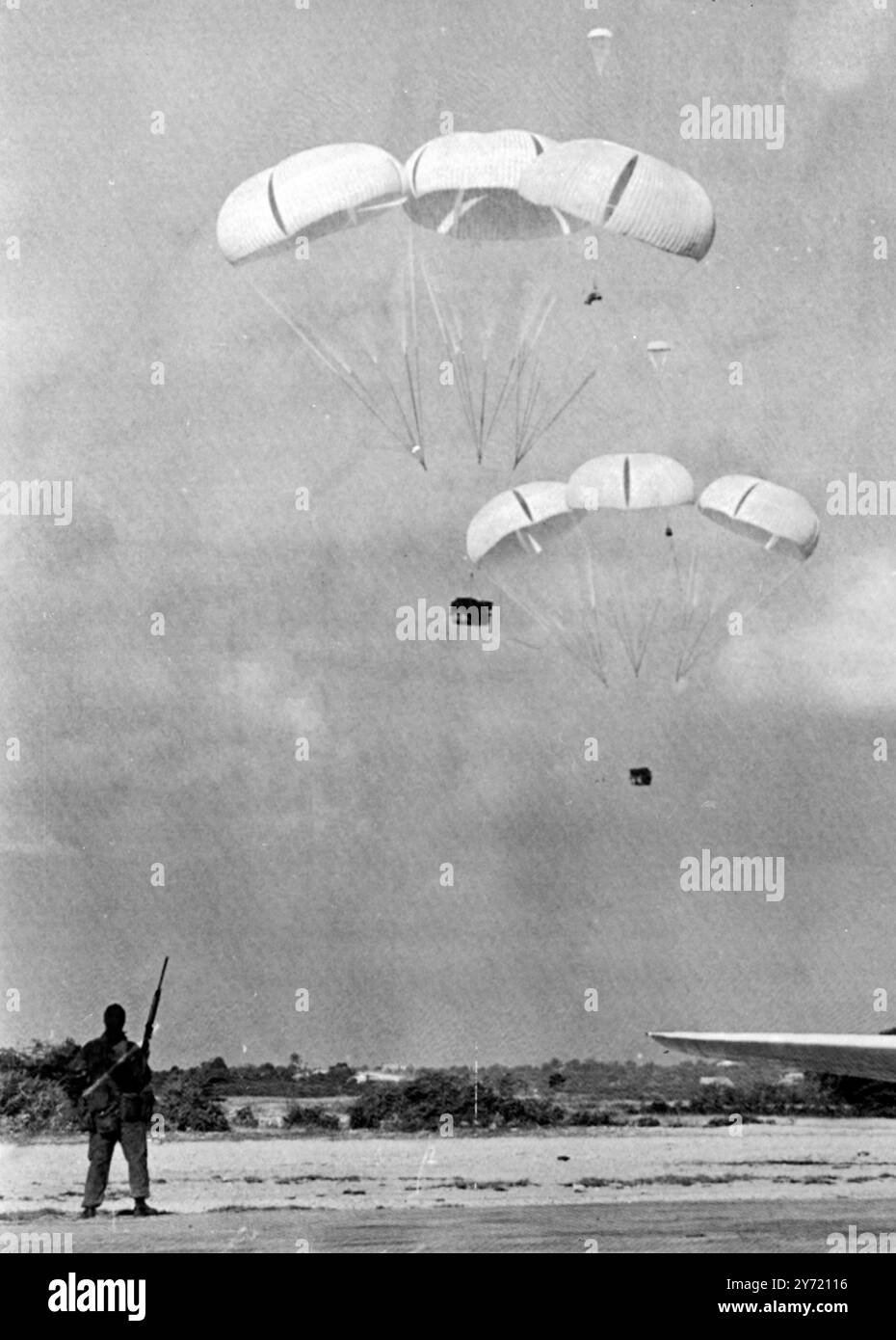 Un soldat britannique se tient debout alors que les fournitures sont larguées en parachute depuis un avion de transport au-dessus de l'aéroport d'Anguilla . Une force de plus de 200 soldats a occupé l'île tôt le 19 mars 1969. Les frégates britanniques Minerva et Rothesay débarquèrent des parachutistes britanniques et des Royal Marines sur l'île , annonçèrent des officiels britanniques à Londres . ' Aucune opposition n'a été signalée ' , a déclaré un communiqué du Commonwealth étranger . Anguilla Antilles britanniques . 19 mars 1969 Banque D'Images