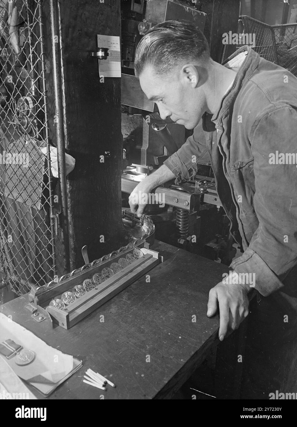 "Accélérer la production à la Royal Mint." La délivrance des médailles du Service général aux anciens militaires s'accélère et, à la monnaie royale, la frappe de 12 000 000 médailles de guerre en cupro-nickel a déjà commencé avec un objectif de 500 000 médailles par mois. Le roi a approuvé la conception le mois dernier. Images : 'Silver Stream' - M. A. Hodge 'frappant' la Médaille de guerre du service général, à la monnaie royale, aujourd'hui (mardi). 16 mars 1948. Banque D'Images