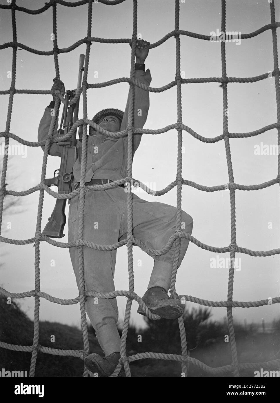 Les hommes de la marine indienne s'entraînent pour reprendre les officiers « Achillies » et les officiers de la marine indienne qui sont en Angleterre pour finalement reprendre le croiseur HMS Achillies suivent des cours dans un humber of Royal Naval Establishment au Royaume-Uni avant la mise en service du navire. À l'heure actuelle, certains d'entre eux sont à Portsmouth où ils apprennent l'artillerie et le combat armé à bord du «navire à terre sèche», le HMS excellent. L'image montre : les classifications navales indiennes s'attaquent à l'obstacle de corde sous l'instruction du Sgt A. R Claydon, DSM Royal Marines, au HMS excellent, Portsmouth. 23 février 1948 Banque D'Images