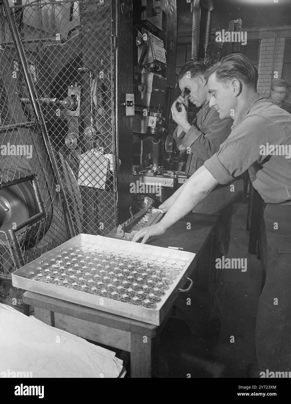 "Accélérer la production à la Royal Mint." La délivrance des médailles du Service général aux anciens militaires s'accélère et, à la monnaie royale, la frappe de 12 000 000 médailles de guerre en cupro-nickel a déjà commencé avec un objectif de 500 000 médailles par mois. Le roi a approuvé la conception le mois dernier. L'image montre : 'Trayful of Treasure' - Mr.C. Ley (caméra la plus proche) guide une rangée de nouvelles médailles de guerre du service général, tandis que M. A. Hodge les inspecte à la monnaie royale, aujourd'hui. 16 mars 1948. Banque D'Images