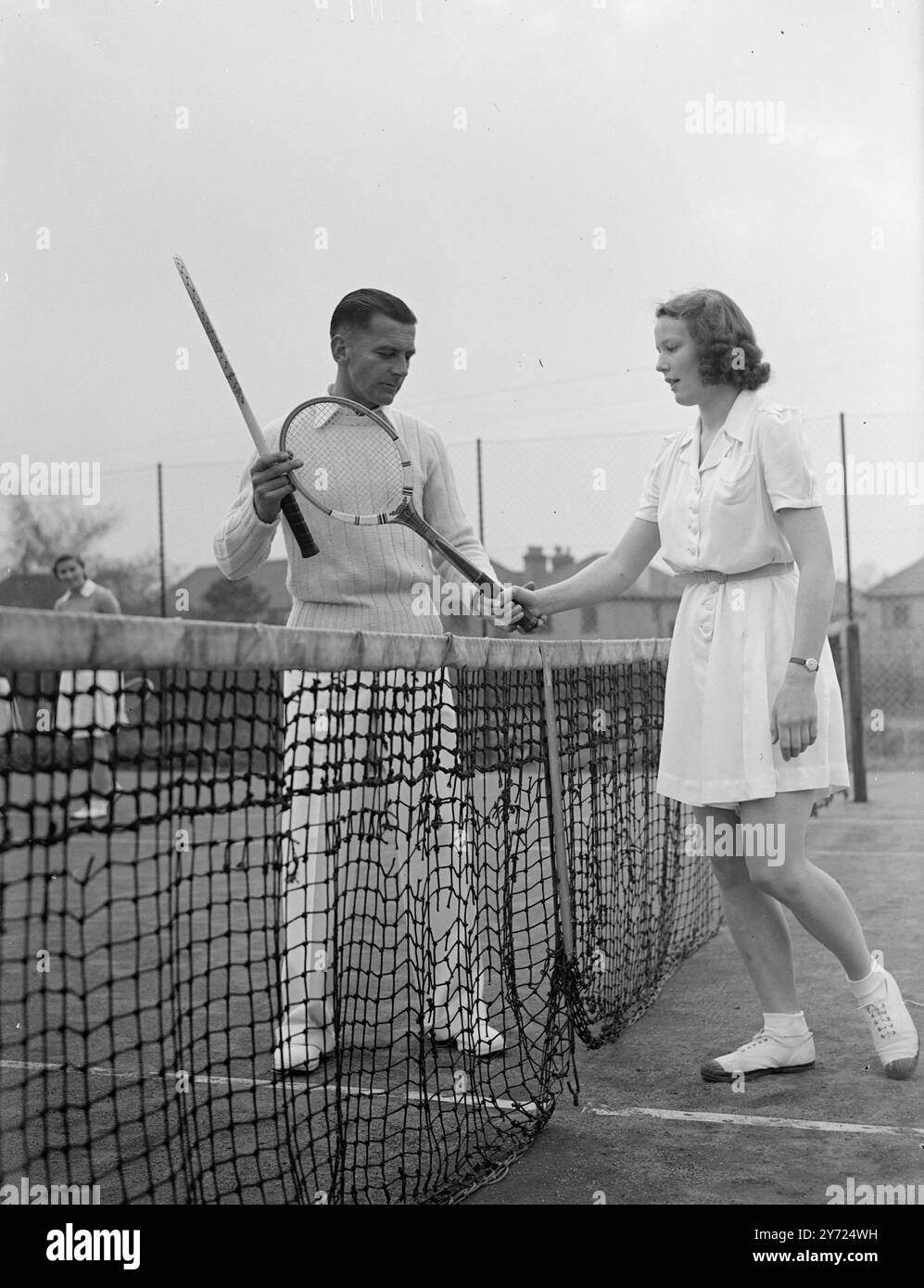 24 garçons et filles, entre 10 et 18 ans, suivent des cours spéciaux de tennis sur gazon au Sundridge Park Club (kent), sur un parcours junior de six à l'invitation du club. Des conférences et des manifestations sur les différents coups sont données par M. J. E Pryor, un entraîneur de Kent, et M. C. B Dniels, le capitaine du club. La photo montre : Ann Miller-Hallett, 17 ans, a sa prise corrigée par Coach J. E Pryor, pendant la pratique à Sundridge Parkl, aujourd'hui (mercredi). 14 avril 1948. Banque D'Images