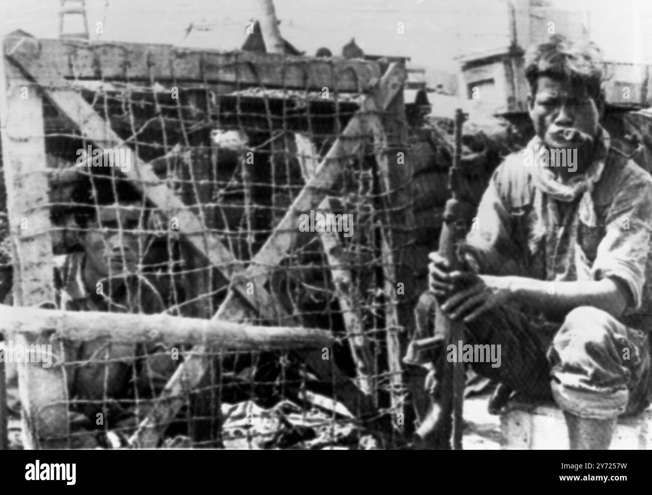 Nord Vietnam régulier mis en cage dans une grande boîte. Plei me , Sud Vietnam ; Un soldat montagnard garde un régulier nord-vietnamien capturé, temporairement enfermé dans une grande boîte au camp des services spéciaux de Plei me avant son évacuation pour interrogatoire et emprisonnement aujourd'hui. Les régiments des Nord-Vietnamiens ont aidé les guérilleros vietcongs dans l'attaque d'une semaine sur le camp. 27 octobre 1965 Banque D'Images