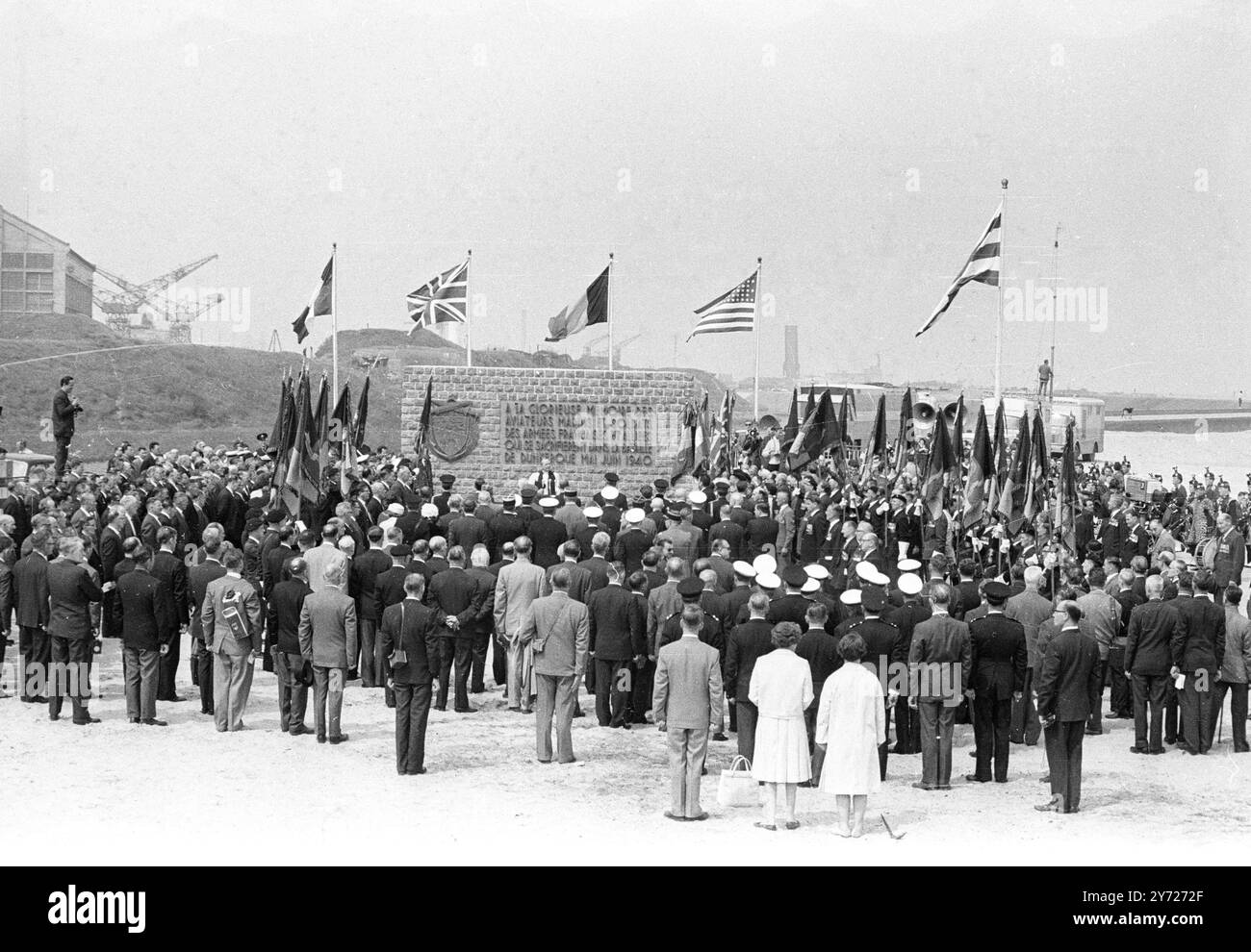 Avec les drapeaux belges , britanniques , français et américains flottant au-dessus du simple mémorial allié sur les plages historiques de Dunkerque , les vétérans du 1940 juin , l'évacuation de la British Expenditionalry Force des plages pendant la seconde Guerre mondiale , les officiers de service et les diplomates rendent hommage à ceux qui ne sont pas revenus pendant les cérémonies ici 5 juin , faisant le 25ème anniversaire de la plus grande évacuation du monde . Quelque 400 hommes des 337 131 qui ont été sauvés des plages dans les premiers stades de la guerre ont assisté aux cérémonies , Dunkerque , France . - - 7 juin 1965 Banque D'Images