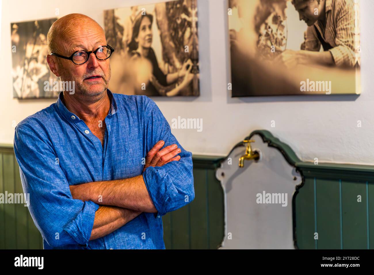 Le viticulteur Christoph Kühne-Hellmessen se tient les bras croisés devant des photographies historiques dans sa cave de Welzin sur l'île d'Usedom, la région la plus ensoleillée de l'Allemagne avec environ 1 900 heures de soleil par an. Sur environ un hectare, il a planté quelque 4 000 vignes en sept variétés ; il a goûté sa première cuvée en 2024. L'agriculteur diplômé, originaire de Bavière, avait auparavant appris la viticulture en Sicile, où il dirigeait sa propre cave. Il a postulé pour cultiver du vin sur Usedom pendant la pandémie de Covid-19 et a planté ses premières vignes en 2021. Welzin, Usedom, Mecklembourg-Poméranie-Occidentale, Banque D'Images