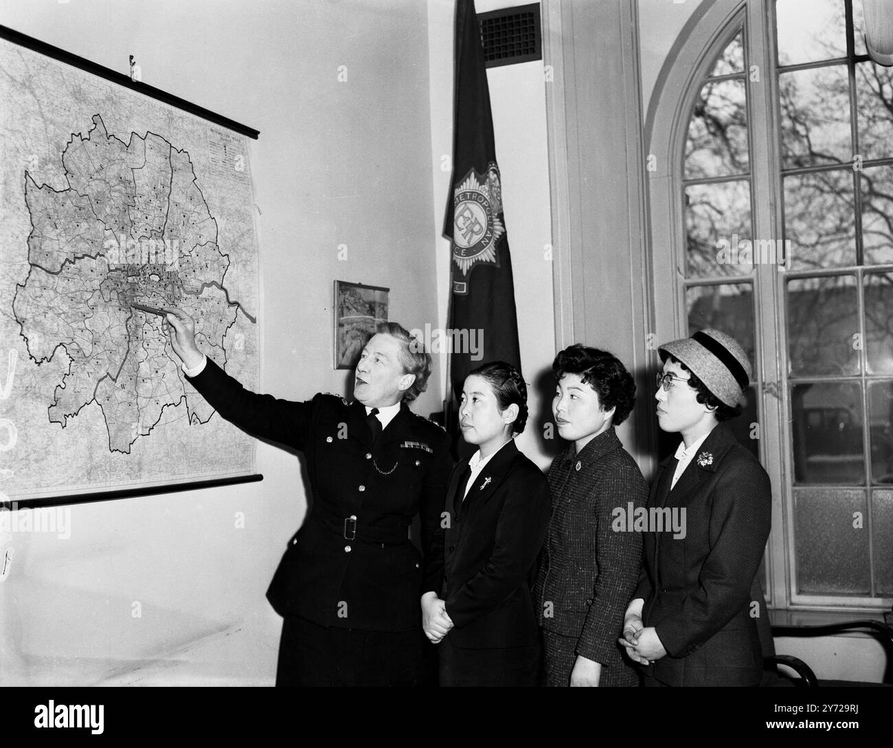 En regardant le Londres métropolitain de la chaleur et de la sécheresse de Scotland Yard , trois syndicalistes japonaises - Superintendent Miss E C Bather , OBE montre , de gauche à droite Miss SAI Hamazaki , Miss Masako Hashomoto et Miss Kiyoko Miyashita , une carte de la région métropolitaine . 20 janvier 1959 Banque D'Images