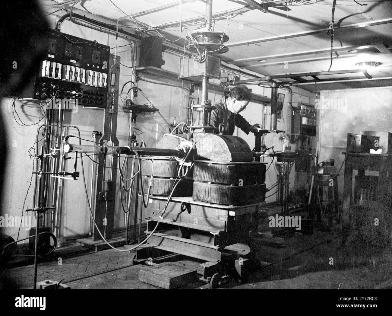 Les deutérons bombardent la 'cible' les deutrons passent dans un champ puissant créé par l'aimant massif à la base du tube. Ils sont tournés le long du tube de verre au centre et laissés frapper sur la «cible» suspendue sous la main de W. Birtwhistle, assistant de recherche dans l'aile Austin, laboratoire Cavendish. La « cible » correspond à un objet dont la structure nucléaire doit être examinée. 24 juillet 1946 Banque D'Images