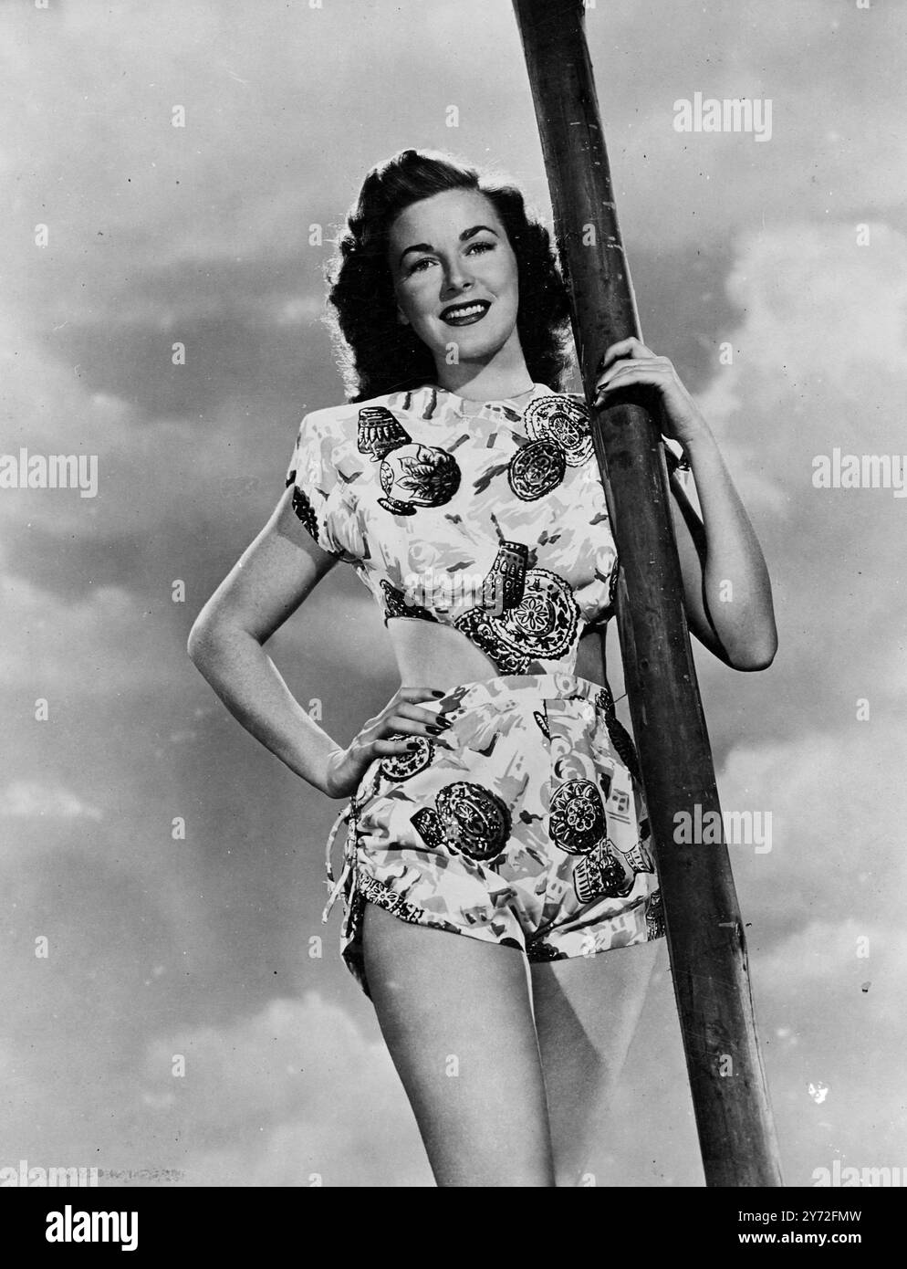 Ce gain que vous placez il est modélisé heureusement par la beauté brune lumière bleue Marguerite Chapman. Elle est une star de Columbia et elle a joué truant des studios assez longtemps pour s'asseoir à la plage dans cette tenue exotique de canicule. L'affaire deux pièces en soie multicolore, ses motifs persans ajoutent une touche orientale à cette playgirl du monde occidental. 20 juillet 1947 Banque D'Images