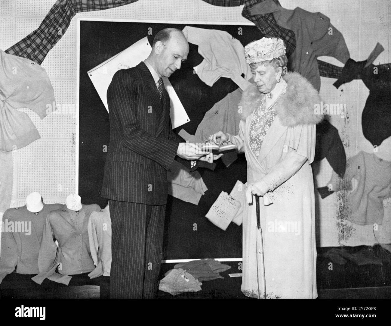 La reine Mary avec M. R.G. Lund, le représentant de la Nouvelle-Zélande, a admiré une paire de chaussures de maison tricotées de couleur gaigre lorsqu'elle a visité l'exposition 'Écosse' du Secrétariat international de la laine à Dorland House, Lower Regent Street, cet après-midi. 18 juin 1947 Banque D'Images