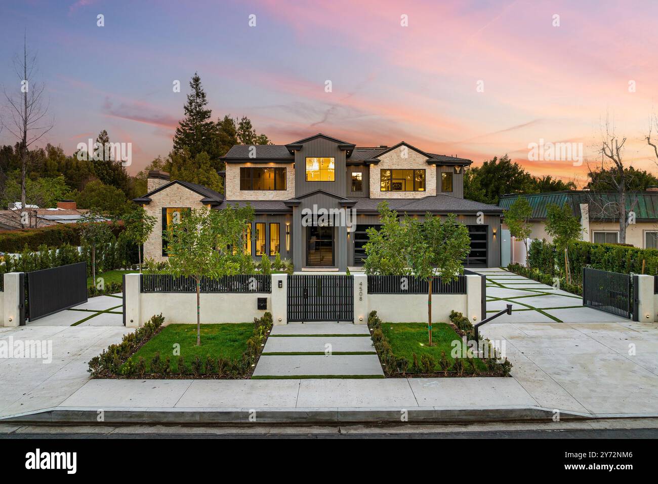 Une maison de luxe moderne avec une pelouse bien entretenue et une allée au coucher du soleil. Banque D'Images