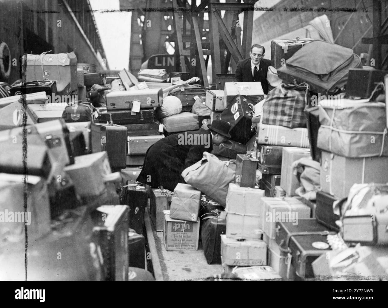 Grève de Lightning Dock à Southampton. Un coup de foudre par des dockers à Southampton aujourd'hui (mardi) a 'bloqué' environ 2000 passagers et plusieurs tonnes de bagages à bord du 'Queen Elizabeth', téléphone venant de New York. Plus tard, les hommes ont accepté de retourner au travail pendant que les négociations se poursuivaient. Des passagers masculins de la « Reine Elizabeth » cherchent leurs bagages dans l'énorme pile qui s'est accumulée lorsque les dockers ont frappé à Southampton aujourd'hui (mardi). Les bagages ont été retirés du navire alors que les stewards des navires sont empilés sur le quai. 25 février 1947 Banque D'Images