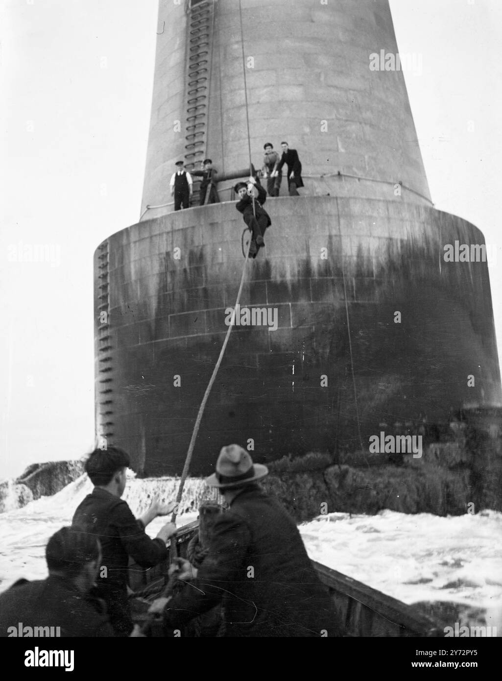 Les hommes de la BBC reviennent à 29 jours sur le phare de tempête. Après avoir passé 29 jours dans la tempête balayé le phare de Bishop Rock, à 7 miles des îles Scilly, le commentateur de la BBC Edward Ward et l'ingénieur Charles Coombs ont été enlevés hier lorsque l'arc en relief a finalement pu traverser le rocher. Les hommes sont allés au phare le 20. Décembre pour faire une émission de Noël et ont été liés par la météo dans la tour de 146 pieds depuis. Photo montre, le gardien Anthony Thomas vient glisser sur la route et dans le bateau de secours et est long et solitaire sort sur la tempête balayé Bishop Rock Lighthouse. 18 janvier Banque D'Images