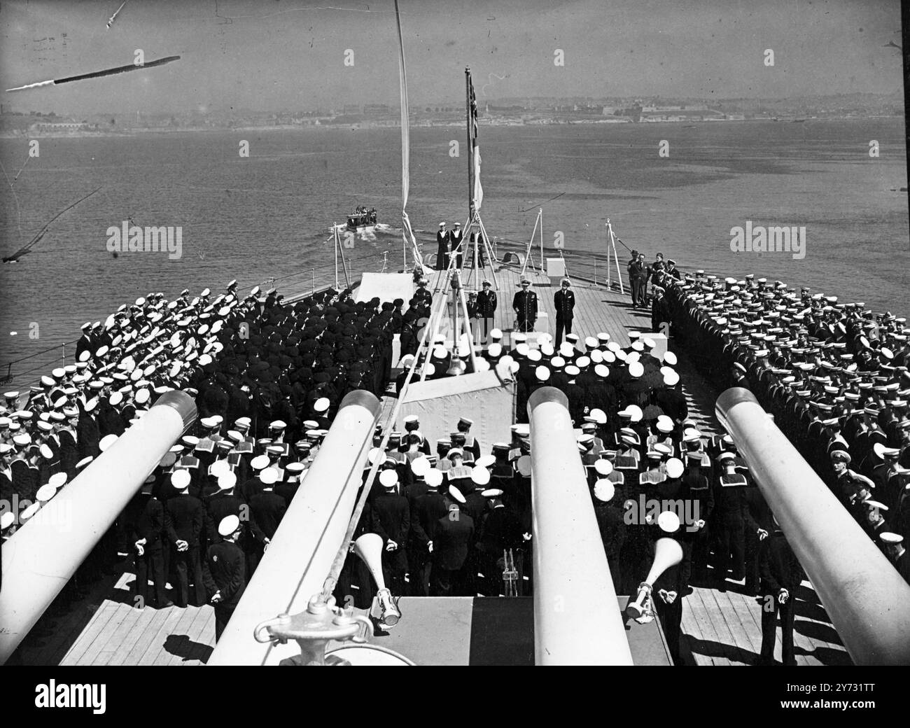 Maison phare du Pacifique. Le HMS Duke of York, navire amiral de l'ancien commandant en chef de la British Pacific Fleet, l'ADML Lord Fraser, est arrivé à son port d'attache de Plymouth hier (jeudi). Après avoir complété une commission de 58 000 miles. Le cuirassé de 35 000 tonnes est accueilli par un salut de 17 canons des batteries côtières, auquel il répond Guenther gun. Le navire restera à Plymouth en attendant l'ajustement de l'effectif, après quoi il devrait rejoindre la Home Fleet. À bord de son œuvre 200 t de nourriture, un cadeau à la Grande-Bretagne de la part du peuple australien. La photo montre, une partie de la compagnie du navire assemblé dessus Banque D'Images