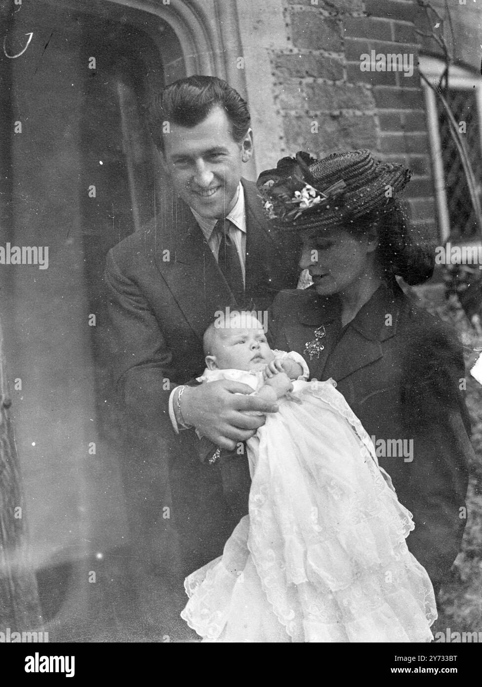 Une foule énorme de fans de cinéma ont moqué Stewart Granger et sa femme à la pittoresque église Linchmere, Haslemere, où leur petite fille Lindsay a été baptisée. Sally Gray était présente comme marraine de l'enfant, mais James Mason et John Mills aussi parrains ne pouvaient pas être là. La photo montre le groupe de christianing. Stewart Granger tenant Lindsay avec Mme Granger. 5 mai 1946 Banque D'Images