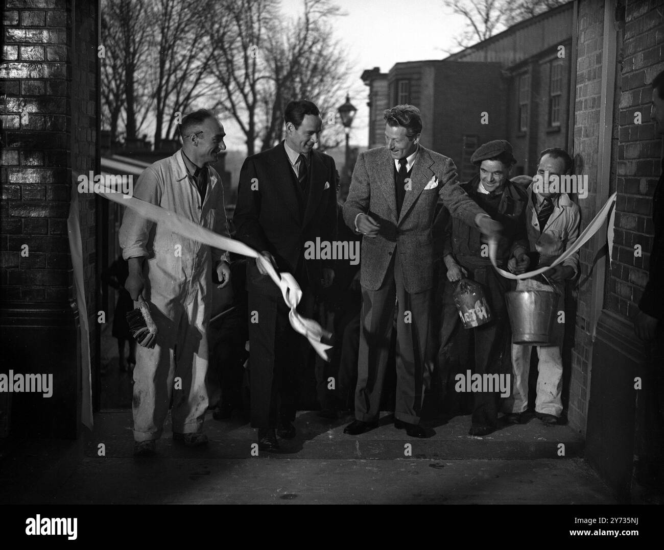 La star de l'écran Danny Kaye est passée aux studios Teddington pour effectuer la cérémonie de réouverture . Les studios ont été reconstruits après le bombardement de juillet 1944 à la suite des efforts de Jack l Warner de Warner Bros Pictures Ltd. Images : Danny Kaye coupe la bande pour rouvrir les studios Teddington reconstruits , sous le regard admiratif des ouvriers du studio . 29 janvier 1948 Banque D'Images