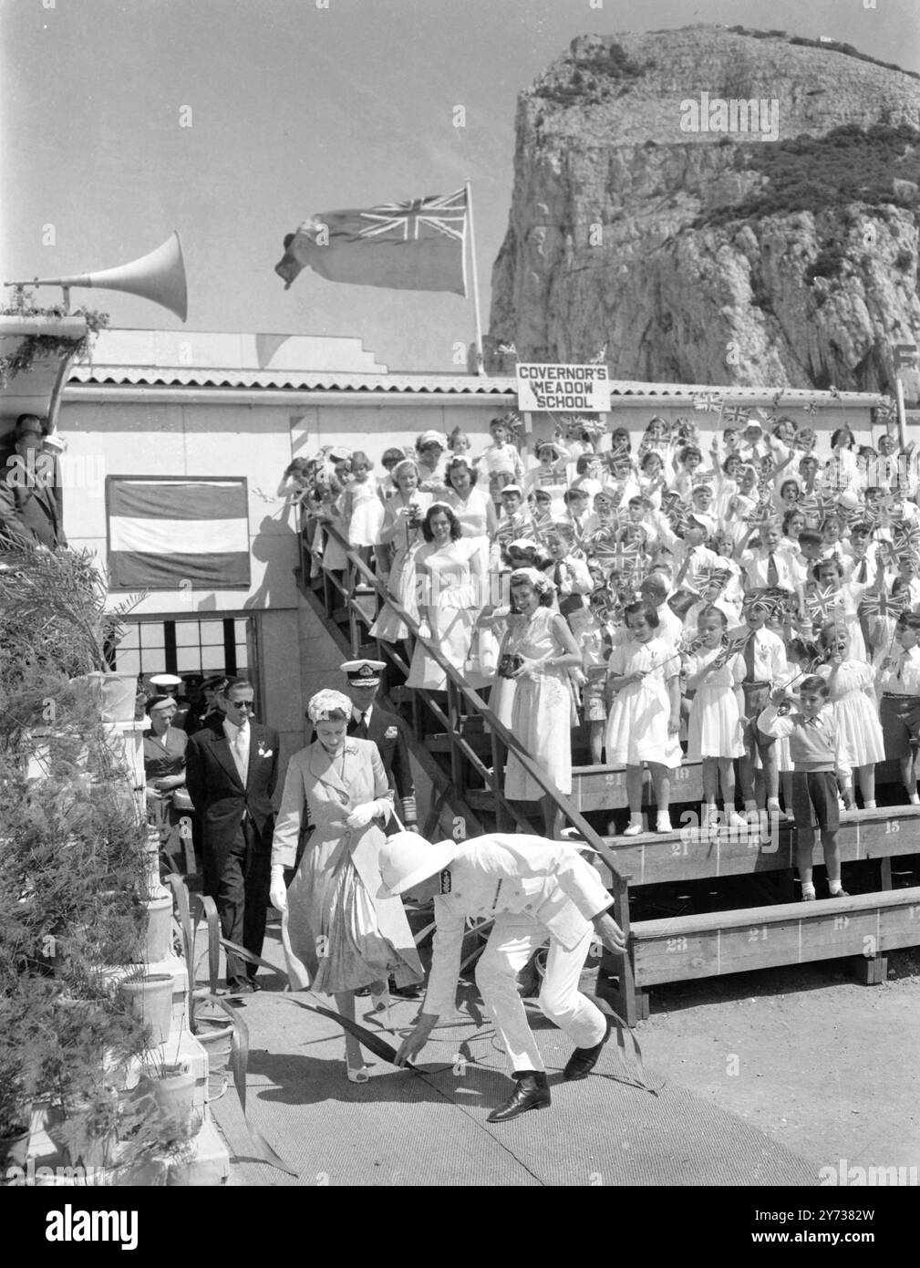 La reine Elizabeth II et le duc d'Édimbourg à Gibraltar en mai 1954, alors qu'ils visitaient le stade Victoria de la Légion britannique , où tous les écoliers de Gibraltar s'étaient rassemblés, sa Majesté a eu des problèmes avec une feuille de palmier qui est retirée de son passage par un officier de marine le 10 mai 1954 Banque D'Images