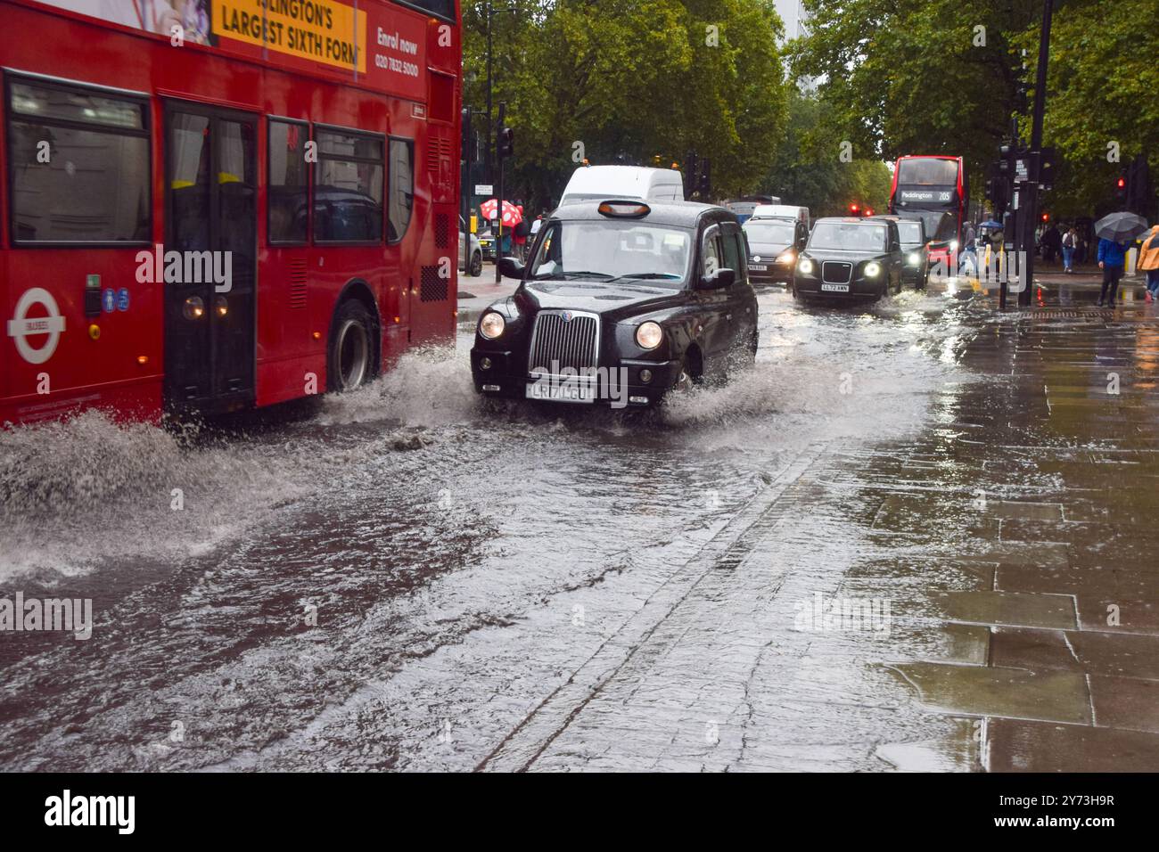 Un taxi éclabousse une Euston Road obstruée par l'eau alors que des avertissements d'inondation sont émis en Angleterre sous de fortes pluies. Banque D'Images