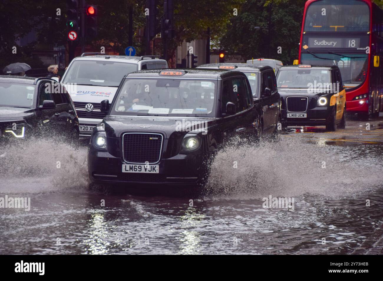 Un taxi éclabousse une Euston Road obstruée par l'eau alors que des avertissements d'inondation sont émis en Angleterre sous de fortes pluies. Banque D'Images