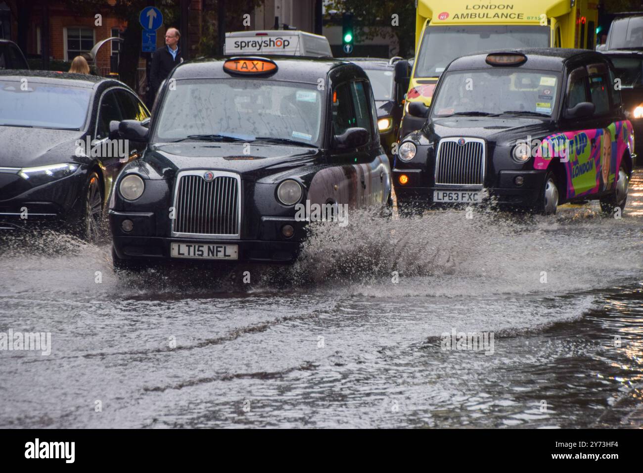 Un taxi éclabousse une Euston Road obstruée par l'eau alors que des avertissements d'inondation sont émis en Angleterre sous de fortes pluies. Banque D'Images