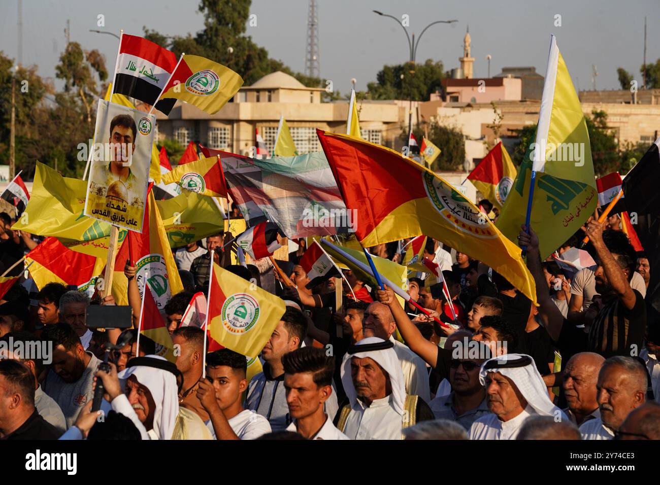 Mossoul, Irak. 27 septembre 2024. Les partisans de la faction armée Kataeb Sayyid al-Shuhada (membre des forces hachées al-Shaabi/de mobilisation populaire ou PMF) tiennent un drapeau lors d'une manifestation de solidarité contre l'agression israélienne contre le Liban et la Palestine près de la Grande Mosquée (non visible) de Mossoul dans la ville de Mossoul, en Irak. (Photo de Ismael Adnan/SOPA images/SIPA USA) crédit : SIPA USA/Alamy Live News Banque D'Images