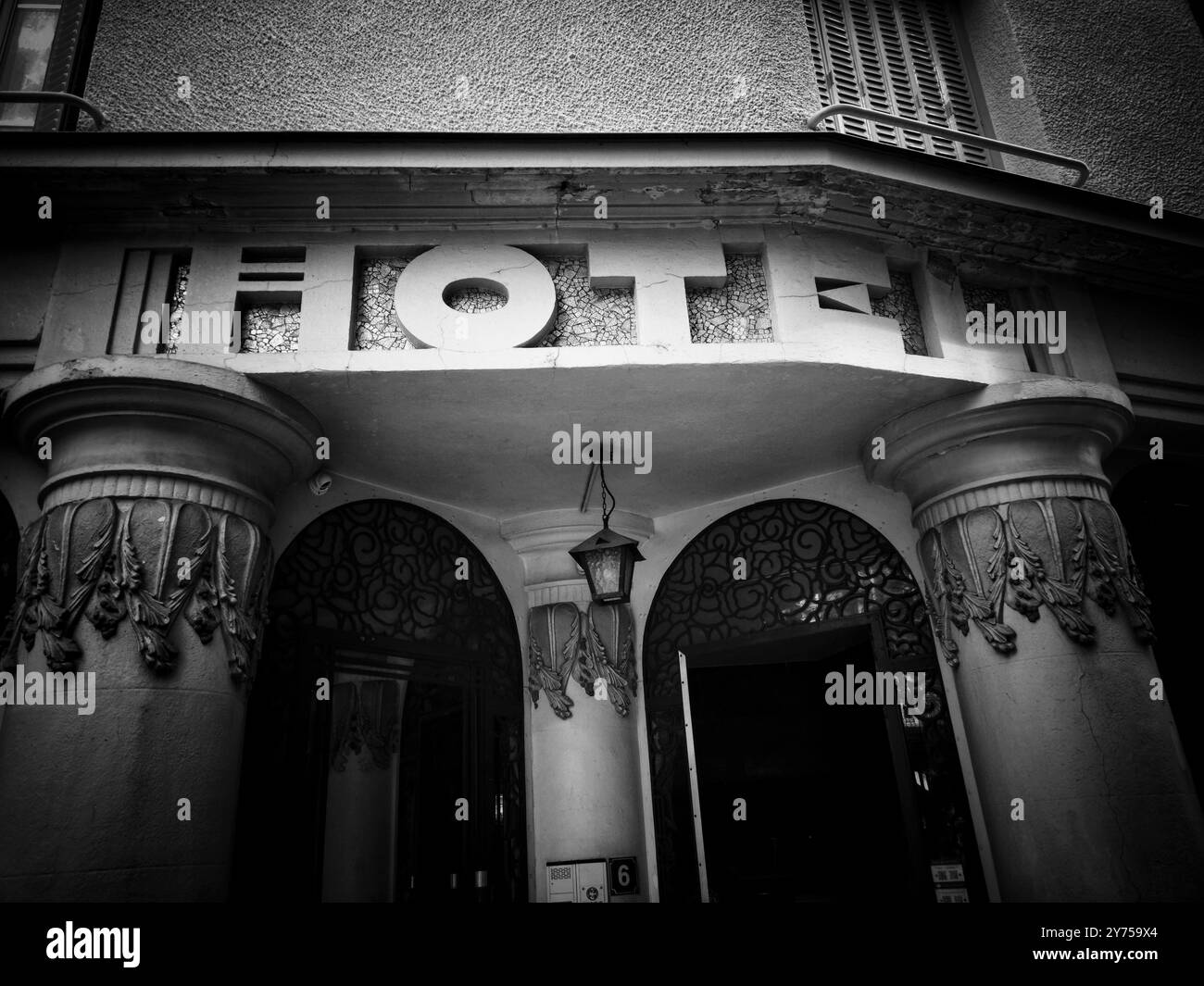 Entrée de l'hôtel avec piliers décoratifs et panneau vintage en noir et blanc capturé dans un cadre urbain animé Banque D'Images