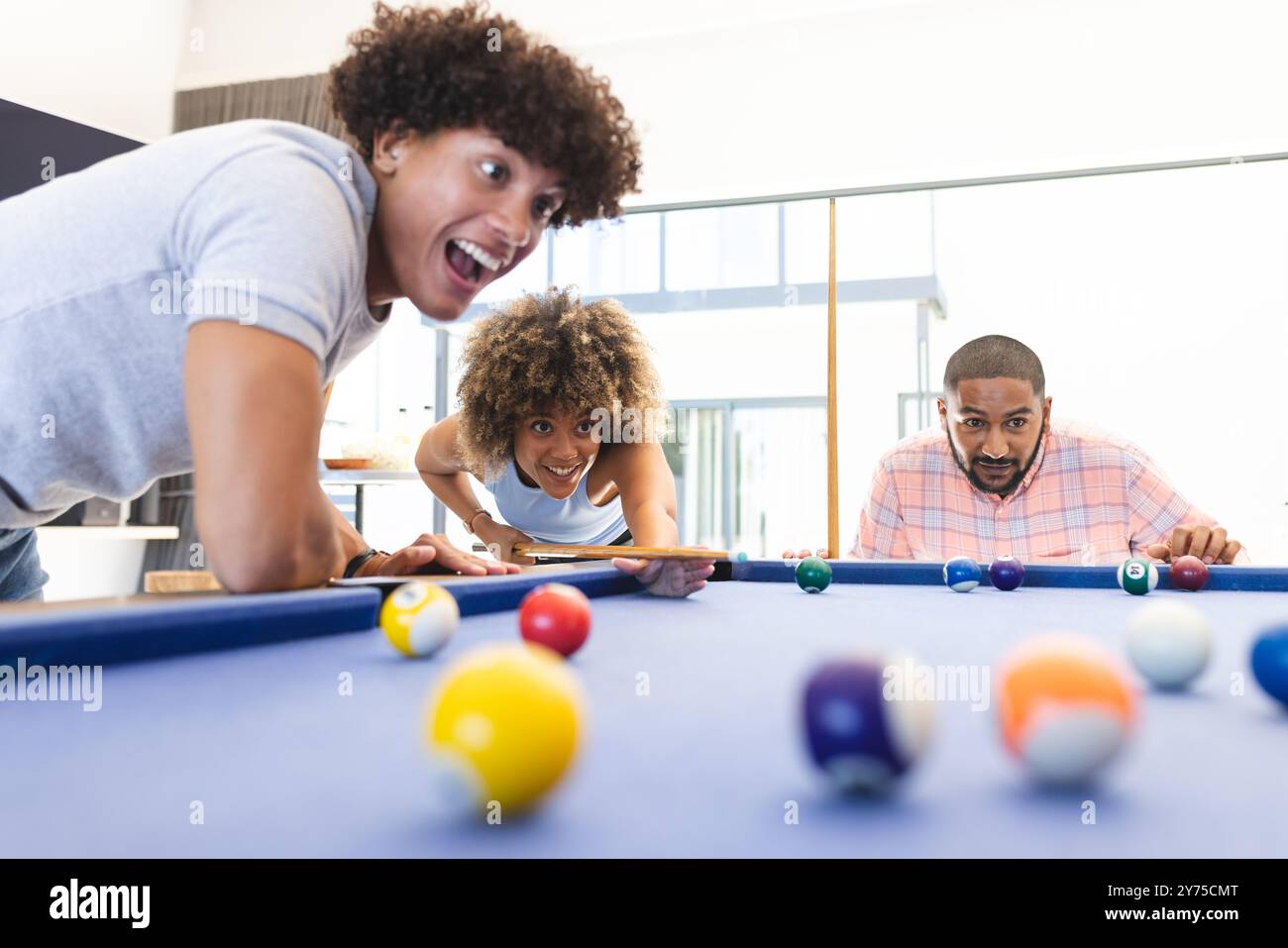 Jouer au billard, des amis divers appréciant le jeu amusant et compétitif ensemble à l'intérieur, à la maison Banque D'Images