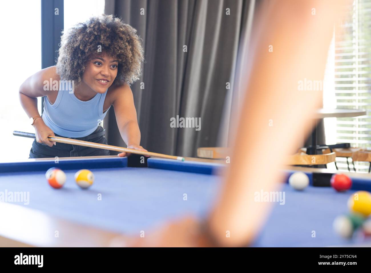 Jouer au billard, femme visant bâton de queue à la table de billard avec divers amis, à la maison Banque D'Images