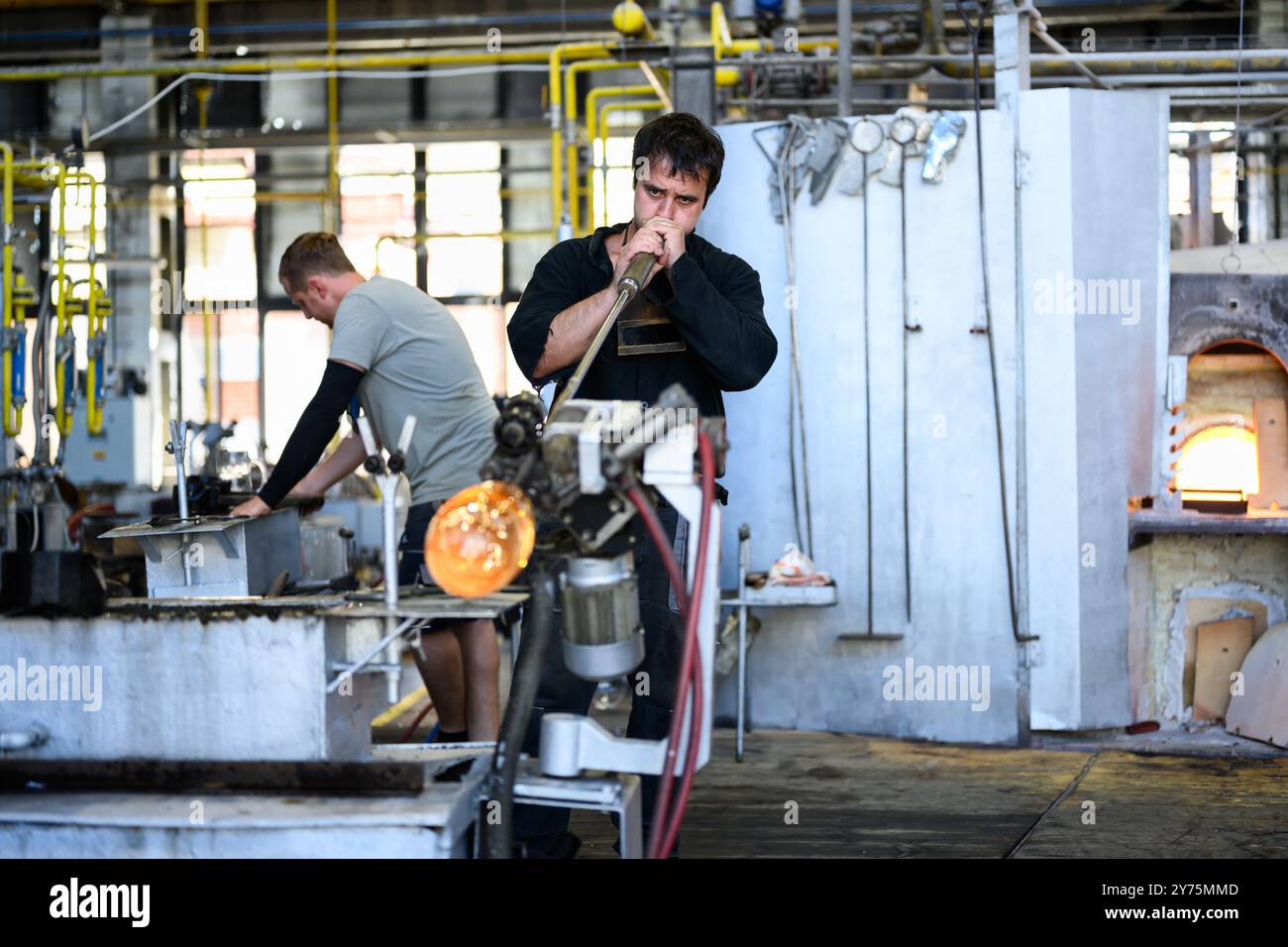 Karlovy Vary, République tchèque - 12 août 2024 : souffleur de verre ou Gaffer soufflant un verre dans l'usine Moser. Banque D'Images